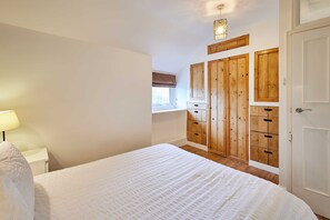 A bedroom with a large bed, wooden wardrobe, and a window with a view. - Host Stay Trefor Cottage (Caernarfon)