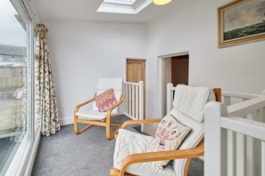 A balcony with two wooden chairs, a white railing, a window with curtains, and a door. - Host Stay Trefor Cottage (Caernarfon)
