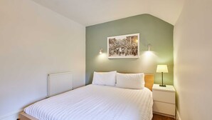 A bedroom with a bed, a nightstand, a lamp, a radiator, and a framed picture on the wall. - Host Stay Trefor Cottage (Caernarfon)