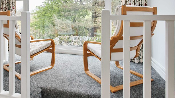 A room with two rocking chairs facing a large window. The window has curtains with a leaf pattern. - Host Stay Trefor Cottage (Caernarfon)