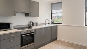 Eine moderne Küche mit grauen Schränken, einem eingebauten Backofen, einer Mikrowelle und einem Fenster mit Blick ins Freie.