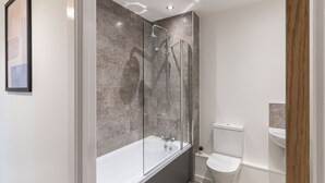 Ein modernes Badezimmer mit einer gläsernen Duschkabine, einer freistehenden Badewanne und einer separaten Toilette.