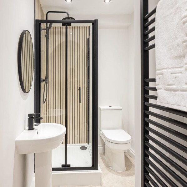 A modern bathroom with a shower enclosure, a toilet, and a sink.