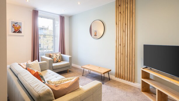 Una sala moderna con un sofá, un sillón y un mueble para televisor.