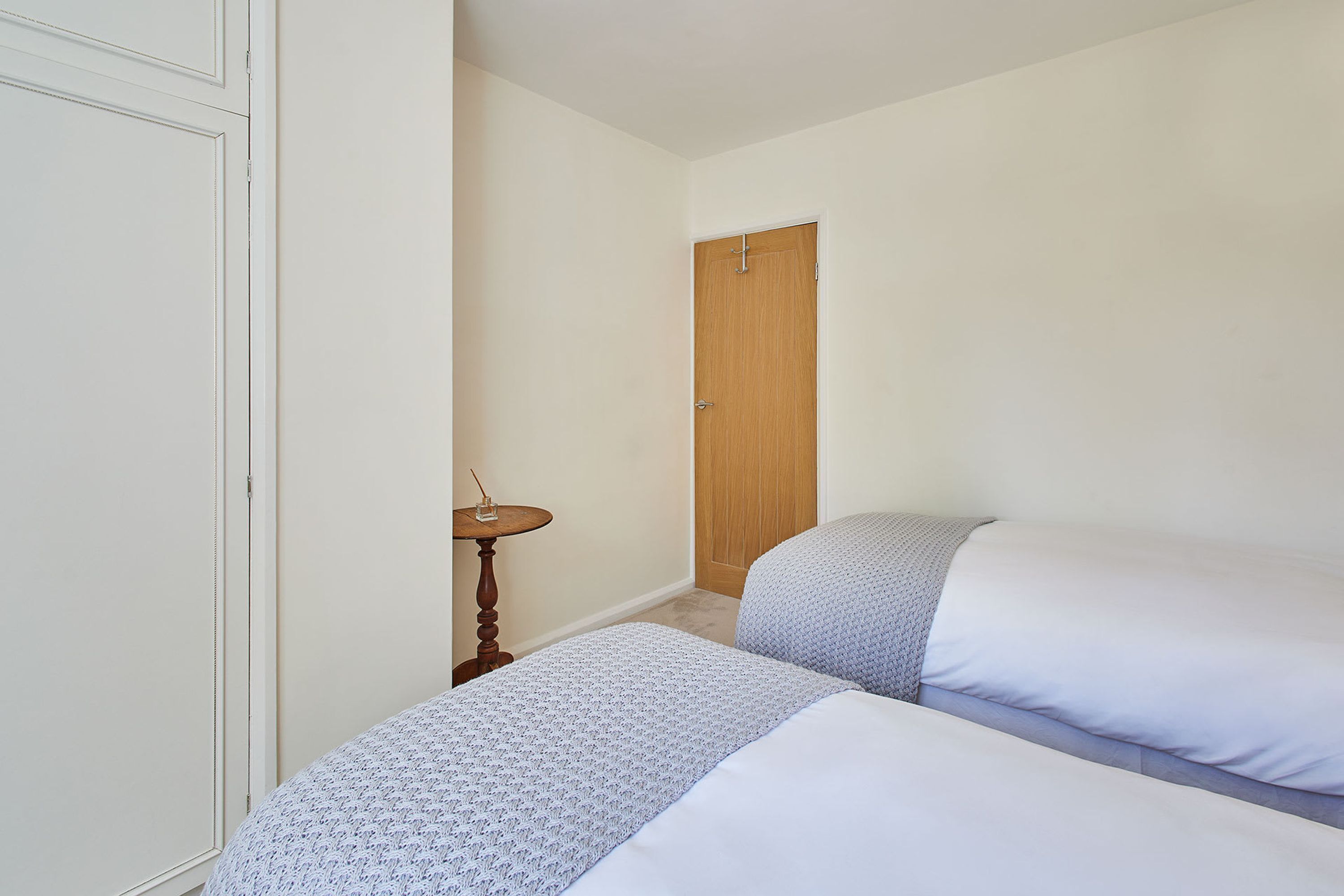 A bedroom with two beds, a wooden door, and a small round table.