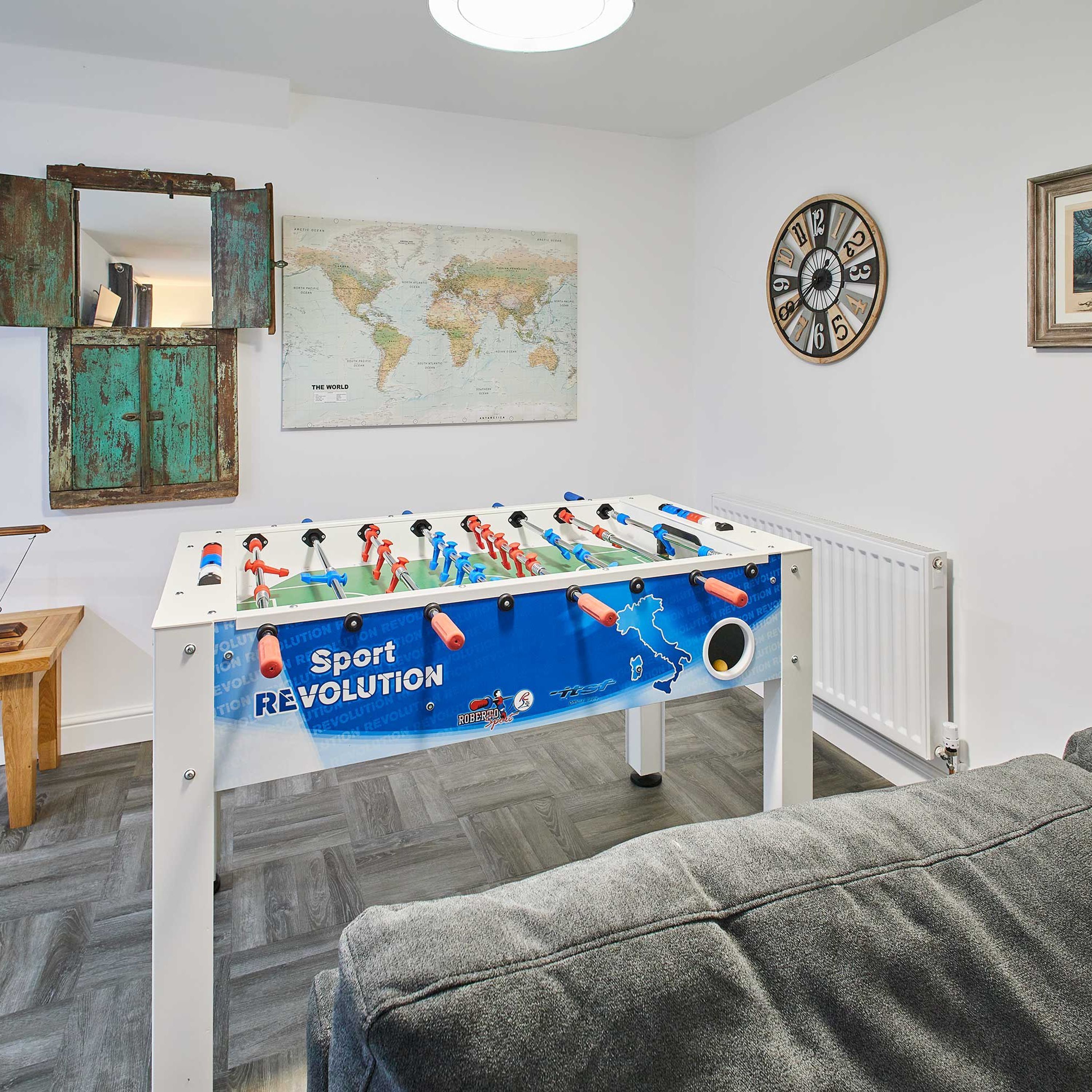 A room with a foosball table, a world map, a clock, and rustic decor.