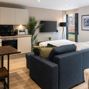 A modern hotel room with a kitchenette, a flat-screen TV, a sofa, and a bed. - Host Stay Richmond Place 003 (Liverpool)
