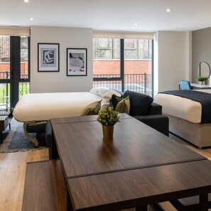 A modern hotel room with a large bed, a sofa, a wooden table, and two framed pictures on the wall. - Host Stay Richmond Place 003 (Liverpool)