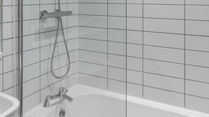 Un baño con bañera, ducha con cabezal de ducha manual y lavamanos.