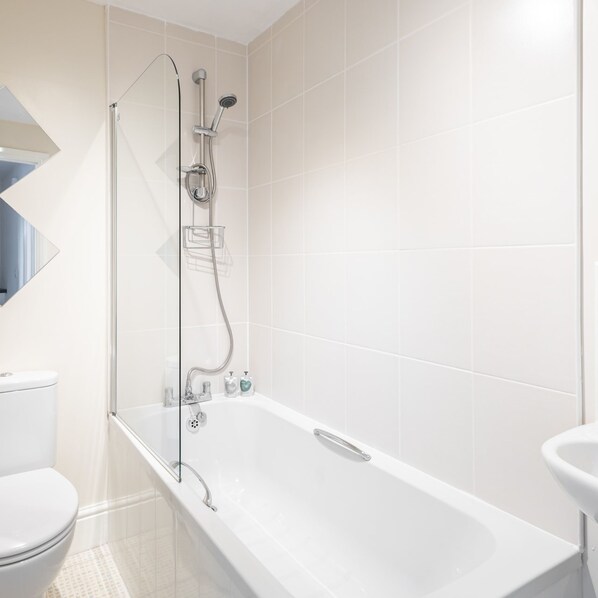 A modern bathroom with a white bathtub, a glass-enclosed shower, and a toilet. - Host Stay Castle Reach (Scarborough)