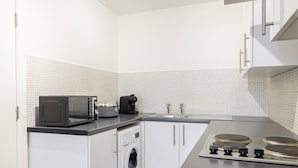 Uma cozinha compacta com máquina de lavar, micro-ondas e fogão.