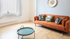 Ein Wohnzimmer mit einer Couch, einem runden Tisch und einem Fenster mit Vorhängen.