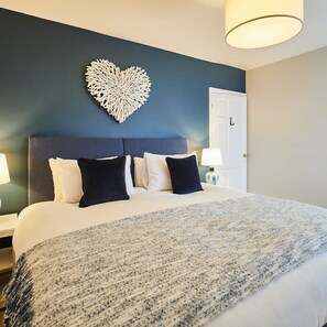 Una habitación de hotel con una cama grande, una decoración en forma de corazón en la pared y una puerta.
