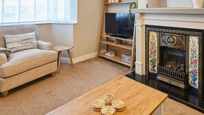 A living room with a sofa, a TV, a fireplace, and a small table with coasters.