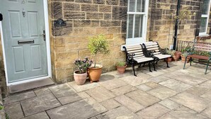 A stone house with a grey door, a bench, and potted plants. - Host Stay Oliver s Den (Alnwick)