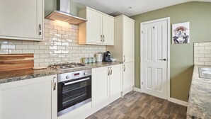 A kitchen with white cabinets, a gas stove, an oven, and a coffee maker. - Host Stay Oliver s Den (Alnwick)