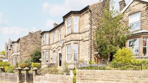 A row of stone houses with bay windows and a stone wall in front. - Host Stay Rock End (Matlock)