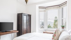 A bedroom with a bed, a television on a wooden table, a wardrobe, and a window with a view. - Host Stay Rock End (Matlock)