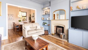 A living room with a fireplace, a television, and a dining area with a table and chairs. - Host Stay Rock End (Matlock)