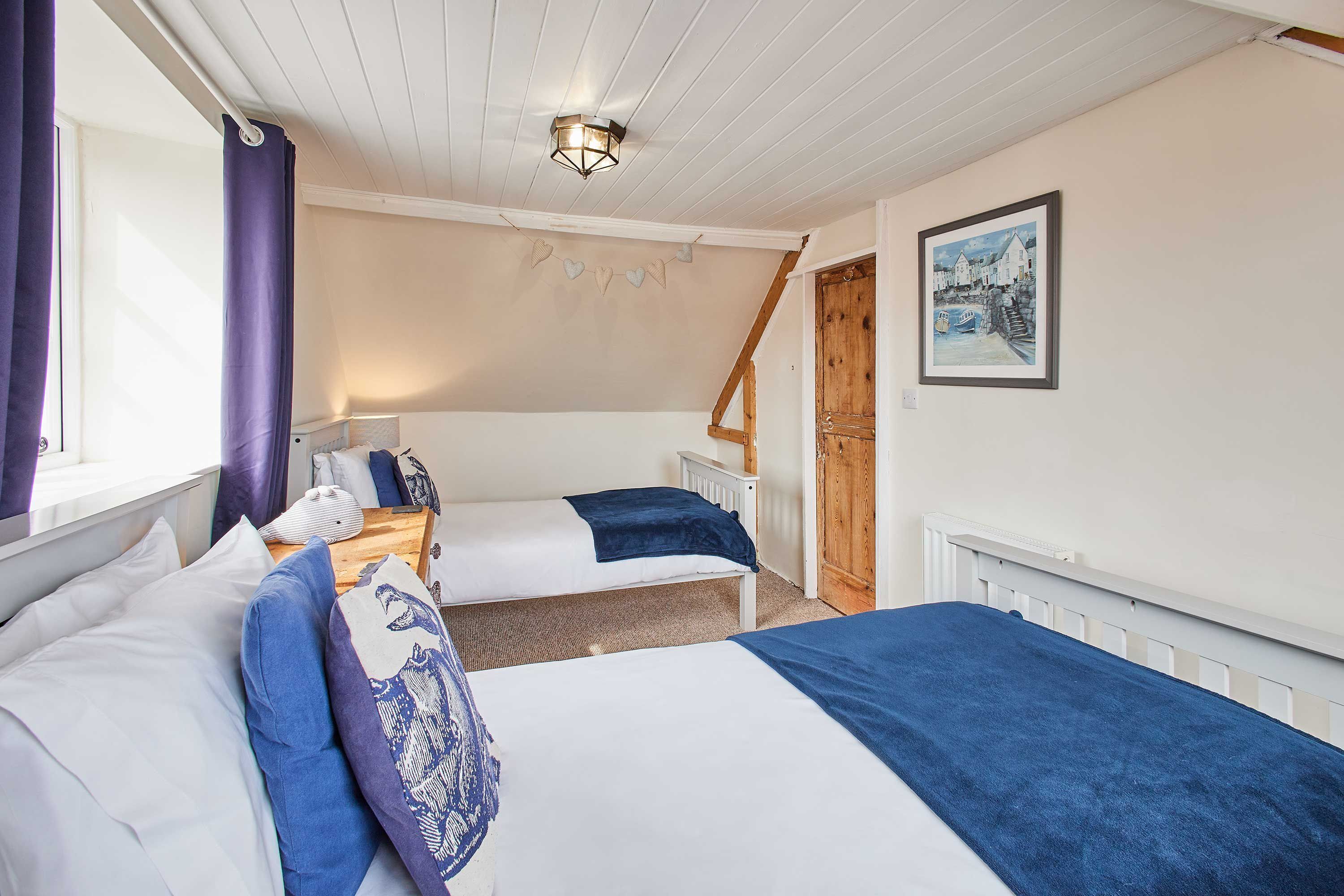 A bedroom with two beds, a wooden staircase, and a painting on the wall.