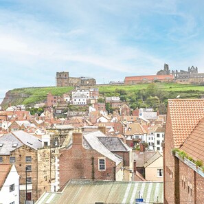 A town with historic buildings and a castle on a hill. - Host Stay The Old Bakehouse (Whitby)