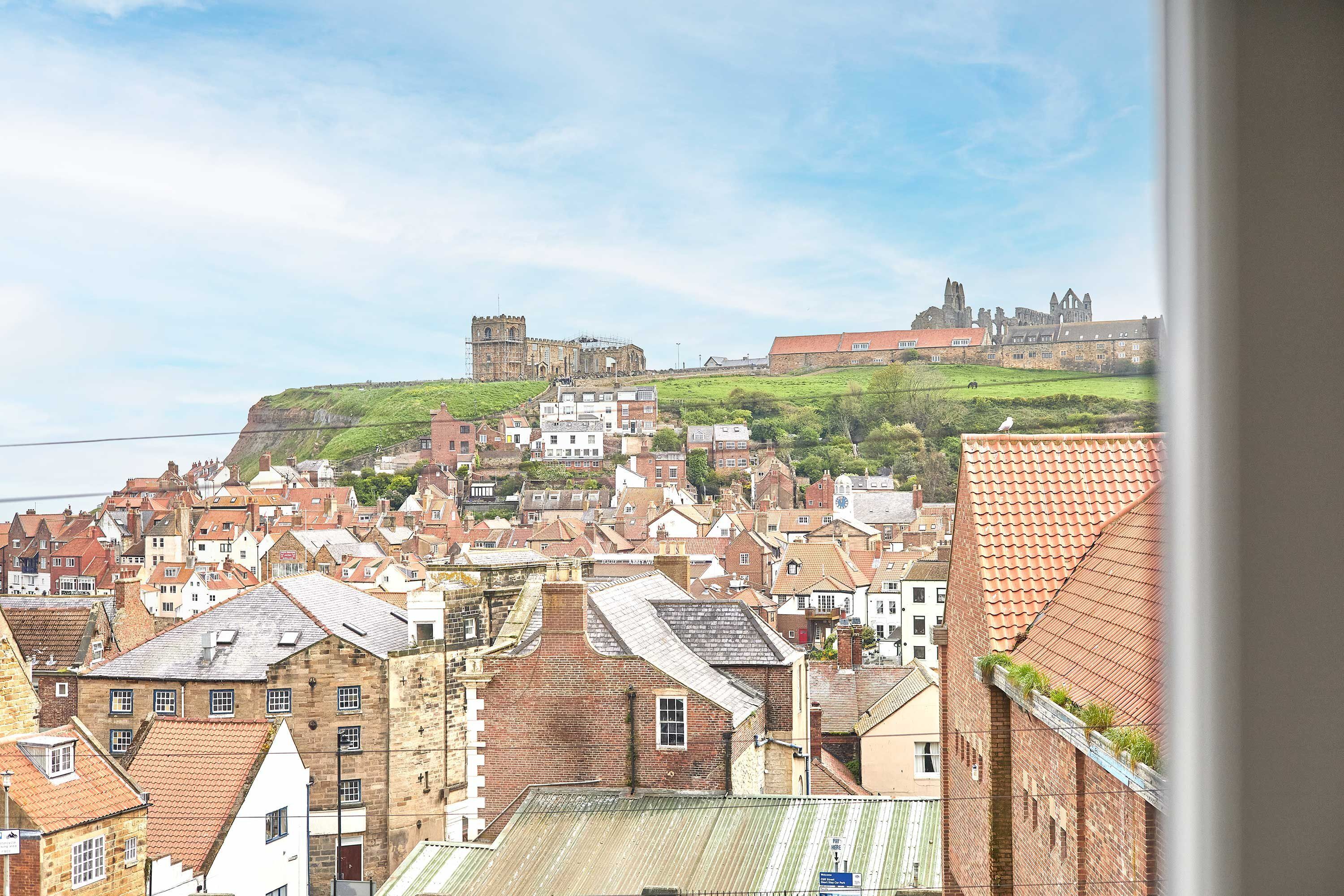 Eine historische Stadt mit einer markanten Burg auf einem Hügel, umgeben von traditionellen Gebäuden.