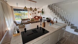 A modern kitchen with a central island, a dining area with a sofa, and a staircase with a unique design. - La Villa Pangea, Havre de Paix Avec vue sur la Rivière et la Nature (Gignac)