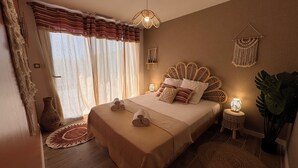 A spacious bedroom with a large bed, a bedside table with a lamp, a macrame wall hanging, and a large plant. - La Villa Pangea, Havre de Paix Avec vue sur la Rivière et la Nature (Gignac)
