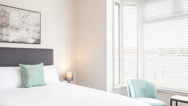 A hotel room with a large bed, a chair, a small table, and a window with blinds. - Host Stay Clifton Studio 5 (Darlington)