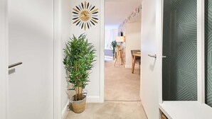 A hallway with a potted plant, a wall clock, and a door leading to a dining area. - Host Stay Apartment 1 Dane Court (Harrogate)
