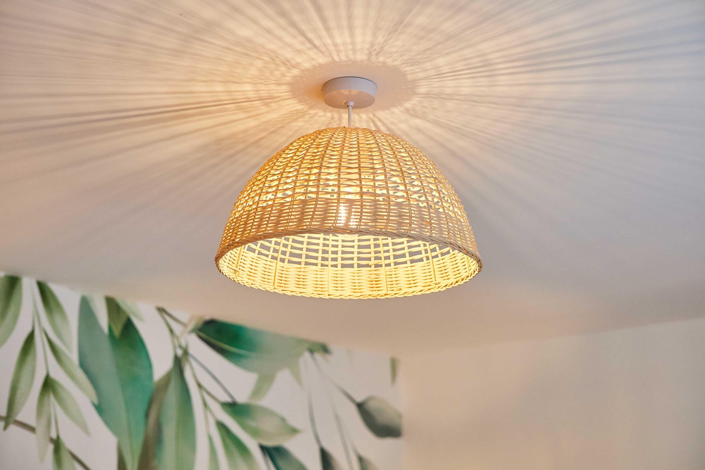 A hanging woven light fixture with a white ceiling.