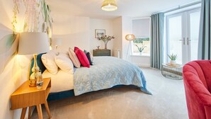 A bedroom with a bed, bedside table, lamp, and a view of the outdoors through a sliding door. - Host Stay Apartment 1 Dane Court (Harrogate)