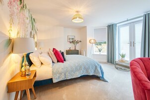 A bedroom with a bed, bedside table, lamp, and a view of the outdoors through a sliding door.