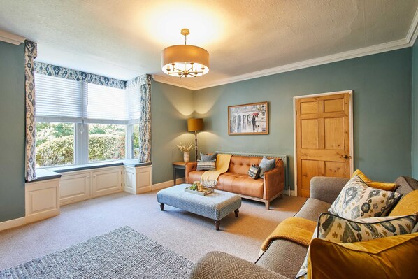 A living room with a large window, a sofa, a coffee table, and a door. - Host Stay May Cottage (Darlington)