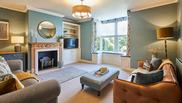 A cozy living room with a fireplace, comfortable seating, and a view through a window.