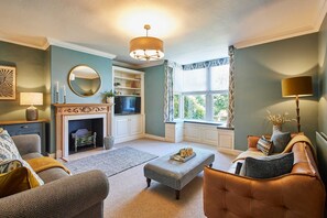 A cozy living room with a fireplace, comfortable seating, and a view through a window. - Host Stay May Cottage (Darlington)