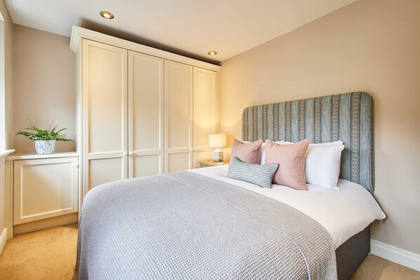 A bedroom with a bed, a nightstand, a lamp, a wardrobe, and a potted plant. - Host Stay May Cottage (Darlington)