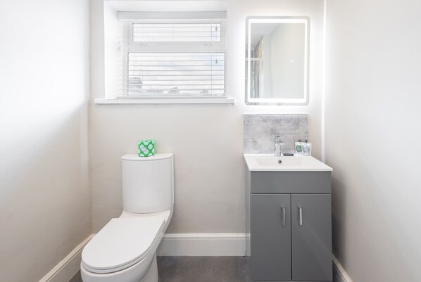 Een kleine, moderne badkamer met toilet, wastafel en spiegel.