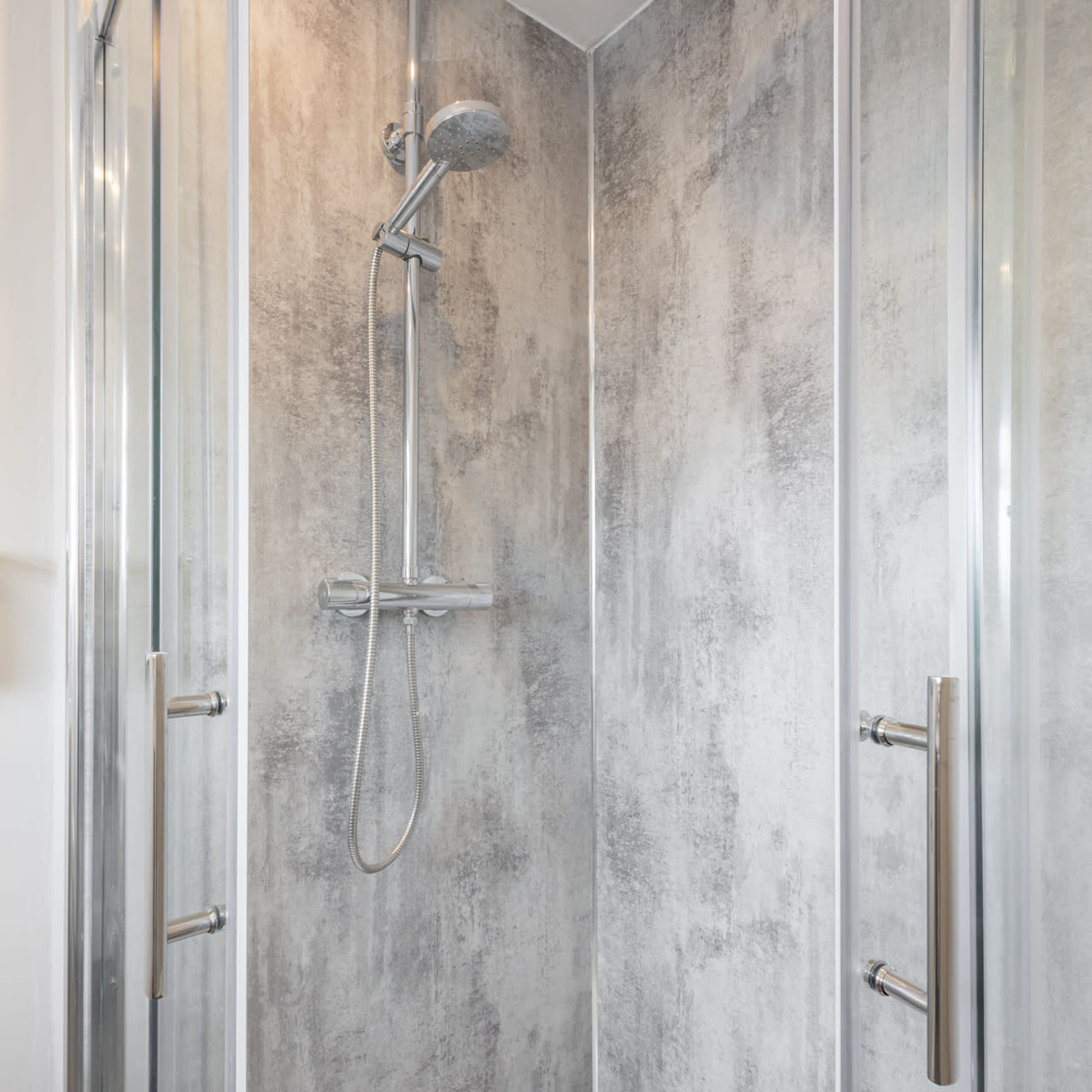 Une douche à l’italienne avec une porte en verre et un mur à texture.