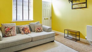 A living room with a grey sofa, a wooden coffee table, a hanging light fixture, and a 'Hello' sign on the wall. - Host Stay Wild Springs (Wetherby)