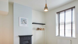 A bedroom with a bed, a fireplace, a radiator, and a window with blinds. - Host Stay Wild Springs (Wetherby)