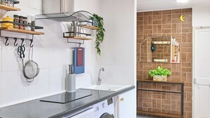 Une cuisine compacte équipée d’un lave-linge encastré, d’un évier et de différents éléments de rangement.
