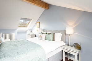 Cozy loft-style room with a large bed, nightstand, and skylight.
