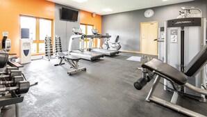 Ein Fitnessstudio mit Laufbändern, Kraftgeräten und Kurzhanteln.