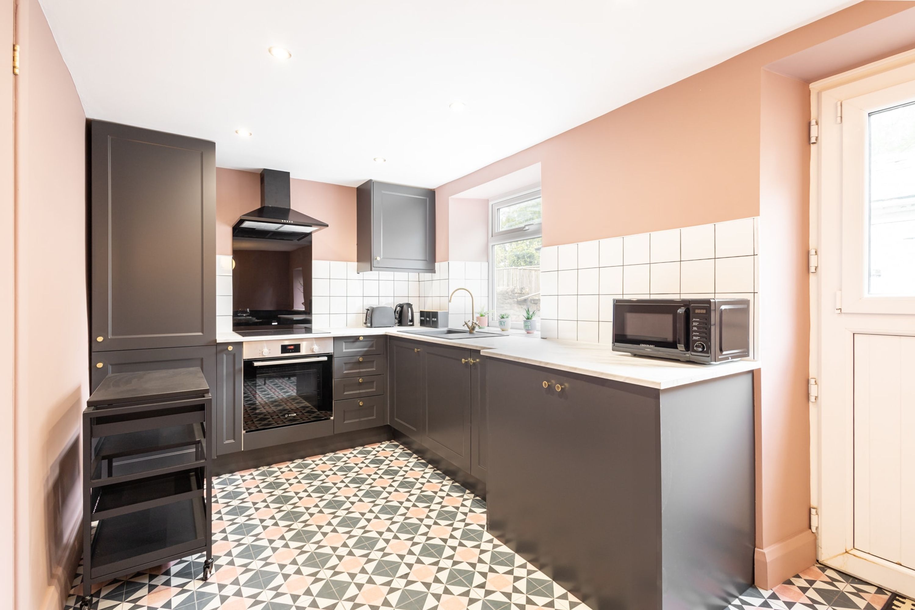 Una cocina moderna con armarios oscuros, un microondas y piso de baldosas.