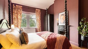 Cozy retreat with a four-poster bed, fireplace, and window with curtains.