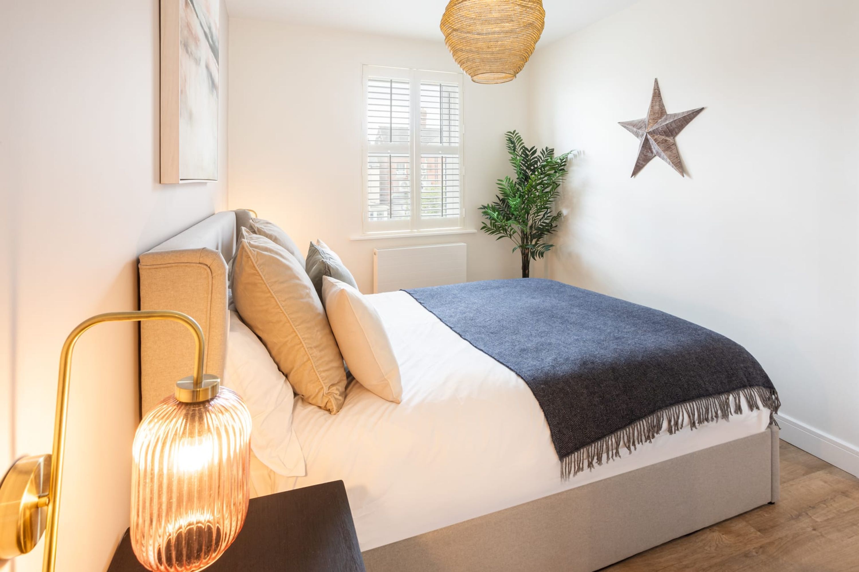 Een slaapkamer met een bed, bedlampje, raam en een decoratieve ster aan de muur.