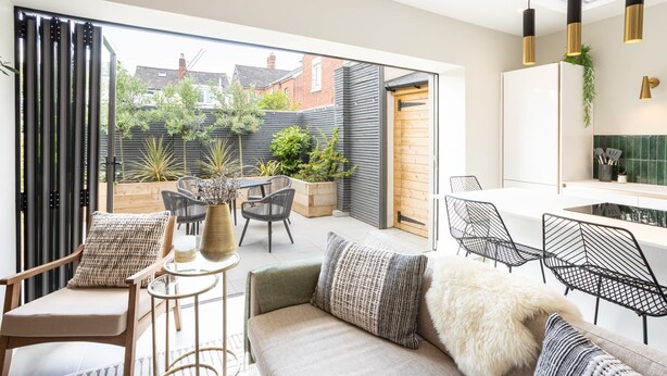 A modern living room with a sofa, chairs, a small table, and a view of the garden. - Host Stay The School House (Hereford)