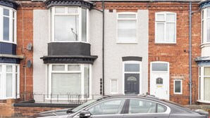 A black car parked in front of a two-story house with a bay window and a front door with a glass panel. - Host Stay Clifton Studio 1 (Darlington)