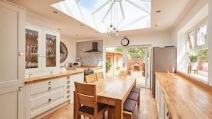 A spacious kitchen with wooden cabinets, a dining table, and a skylight. - Host Stay Bankside Cottage (Saltburn-by-the-Sea)